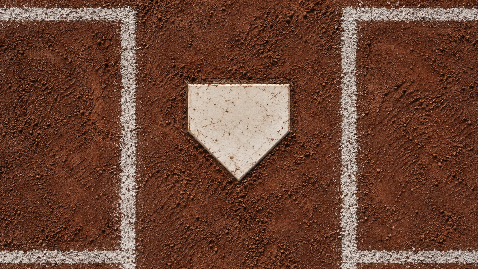 A home plate and crisp chalk lines on a textured baseball infield.